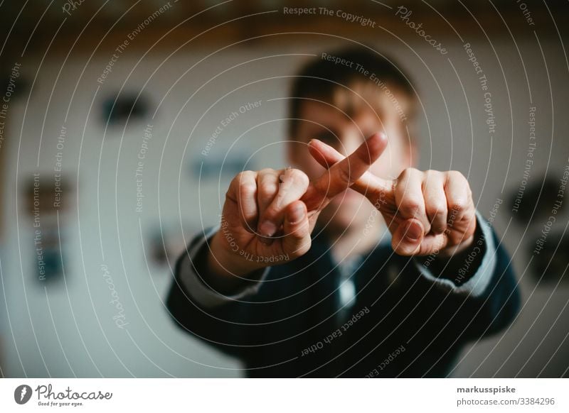 Boy makes a cross with his fingers Boy (child) Infancy Children's game Fingers hands Symbols and metaphors symbolic power Symbolism Rotate Rotated Middle finger