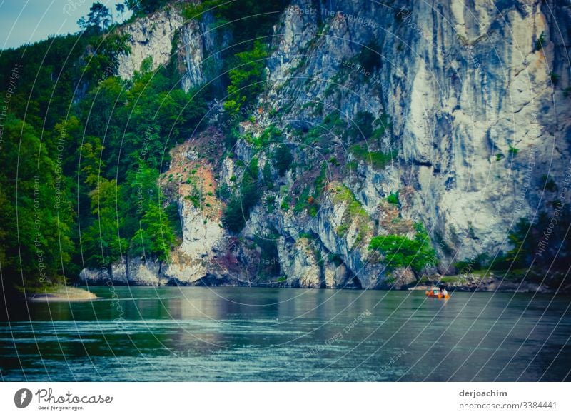 Danube breakthrough. With big rocks and strong current. A small red boat is to be seen in the lower edge. On the left a group of trees. River Narrow Rock