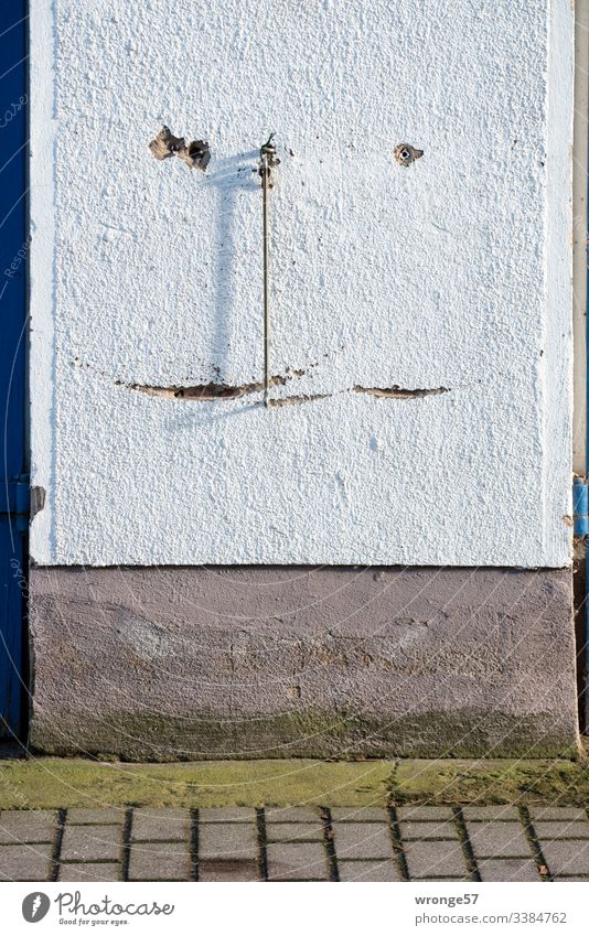 A steel hook hangs down between 2 gates Checkmark Fastening Goal Backup Scratch mark grooves traces of use Plaster Rendered facade garage wall Shadow play