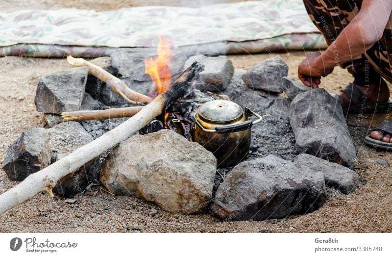 old kettle by the fire and people sitting next in Egypt Dahab South Sinai Bedouin tea Bedouins Middle East ashes bask beggar broken camouflage cook crisis