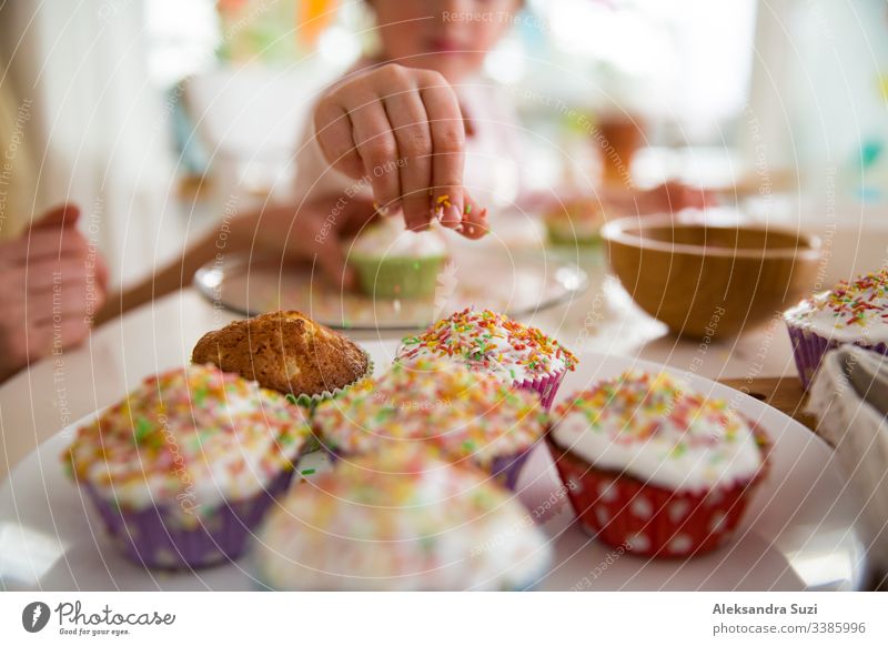 Mother and daughter celebrating Easter, cooking cupcakes, covering with glaze. Happy family holiday. Cute little girl in bunny ears. baking candid celebration