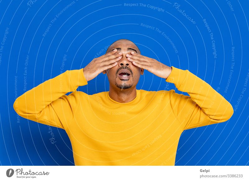 African guy with a yellow jersey black surprised exciting crazy happy emotion cover eyes blind closed blue adult people person african male american man