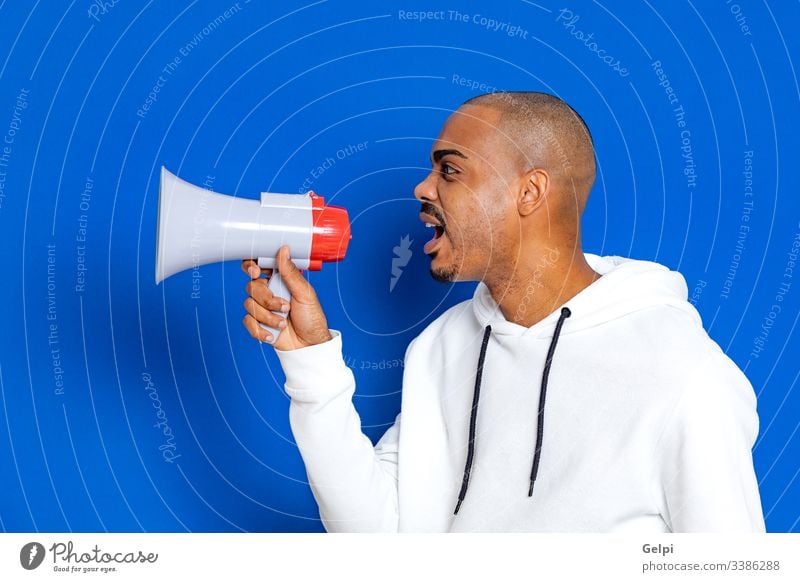 African guy wearing a white sweatshirt black blue megaphone loudspeaker yelling shout announce voice shouting communicate announcement ad advertisement adult