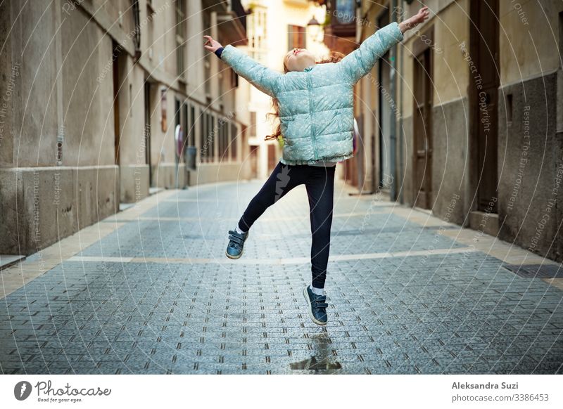 Cute little girl dancing on city street. Narrow streets of Palma de Mallorca old town. active beautiful carefree child childhood children concept cool dance