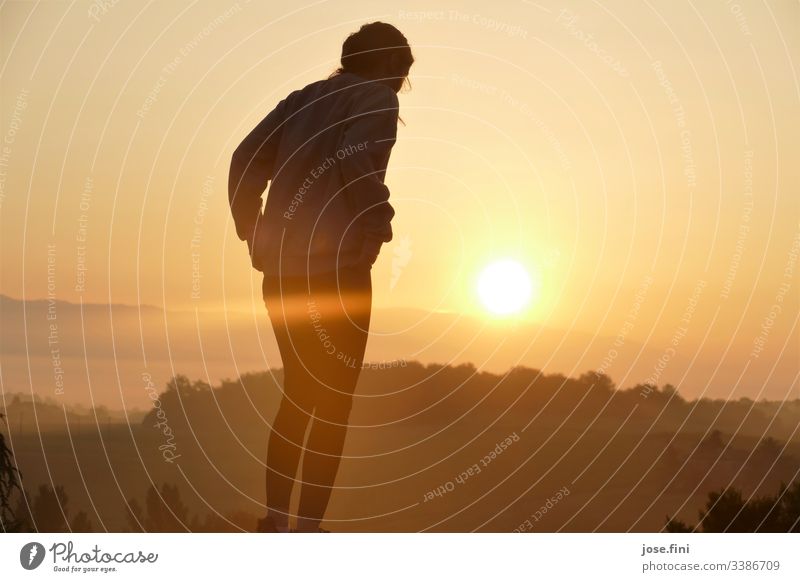 Woman stands before sunrise in the Toscana Nature Landscape trees mountains Horizon Sky Sunlight Sunrise Orange Bright rays Exterior shot Yellow Morning clear