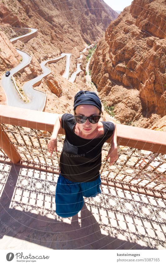 Image of female tourist relaxing on a terrace ovelooking winding road in Dades Valley, Atlas mountains, Morocco. morocco dades valley gorge woman adventure