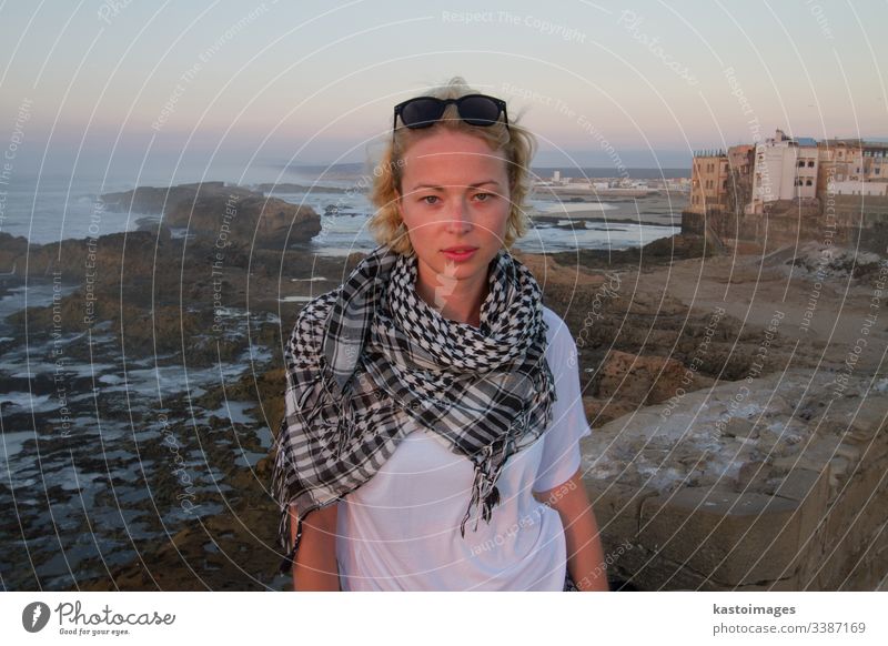 Female traveler standing on city fortress wall of Essaouira, Morocco in sunset. adventure girl explorer journey woman lifestyle freedom outdoor tourism young