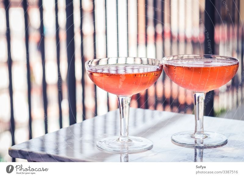 Two crystal stemmed glasses with rose wine on marble table outdoors. Aperitif time white party pink drink dinner luxury light background modern alcohol bar