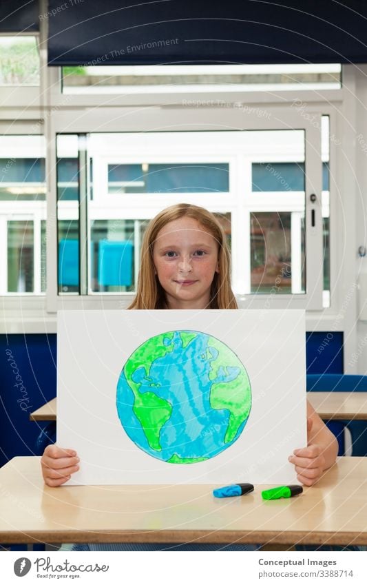 Primary school caucasian girl holding placard with an image of the earth drawing planet schoolchild environment female education ecology future conservation