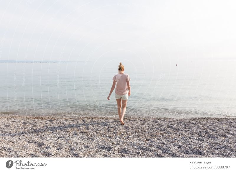 Happy Carefree Woman Enjoying Sunset Walk on White Pabbled Beach. beach sun sea girl happy nature young female summer water ocean beautiful vacation freedom