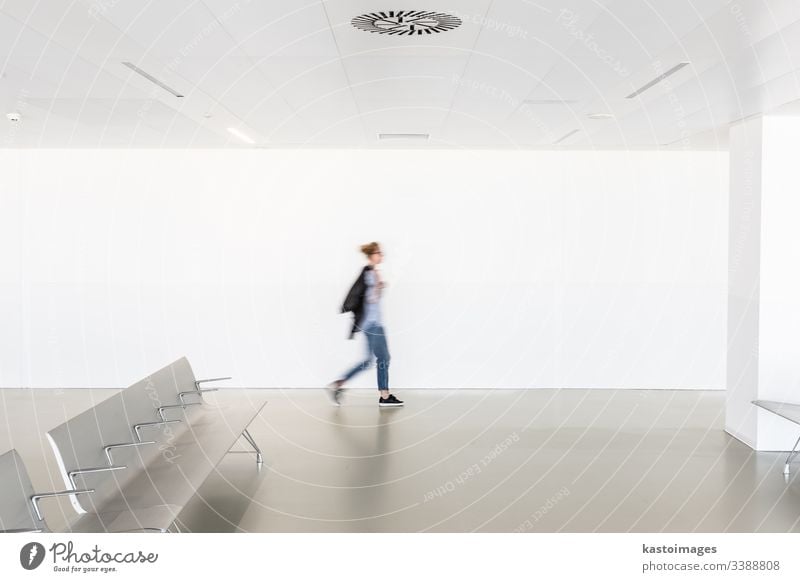 Motion blur of woman walking at contemporary white empty hallway interior architecture motion seats terminal modern room caucasian female blurred health light