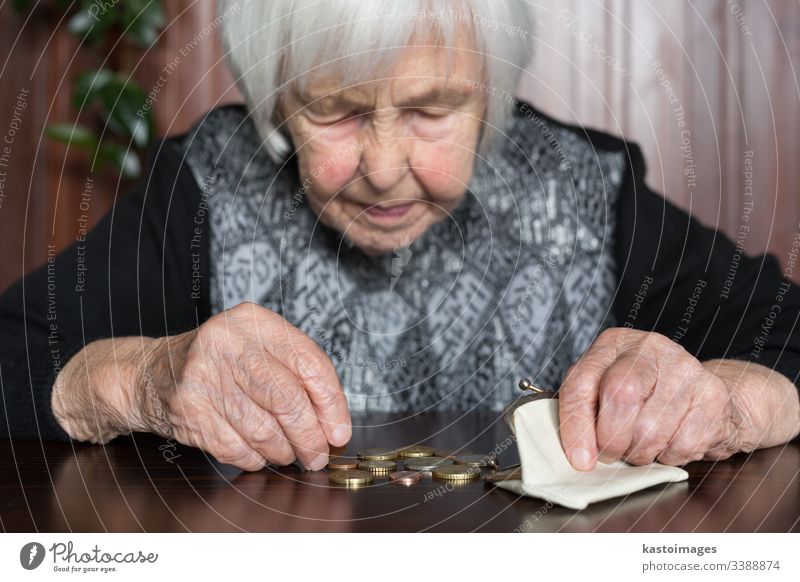 Elderly woman sitting at the table counting money in her wallet. senior pensioner elderly poverty retirement old empty coins background miserable broke lonely