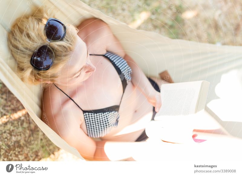 Woman reading book in hammock on the beach vacation day female woman relax young novel relaxation rest summer leisure lying human idyllic person resort relaxing