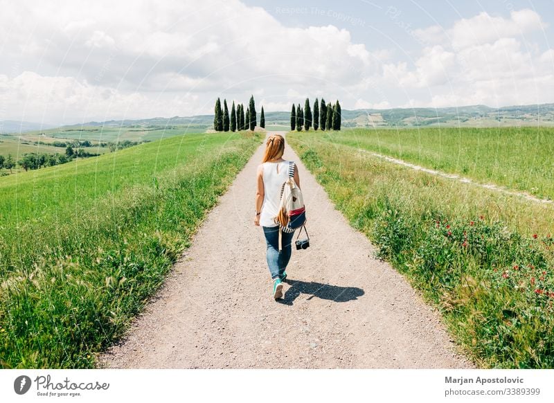 Young female traveler walking in Tuscany countryside beautiful camera casual cypress cypresses dreamland enjoying europe european explorer girl green holidays