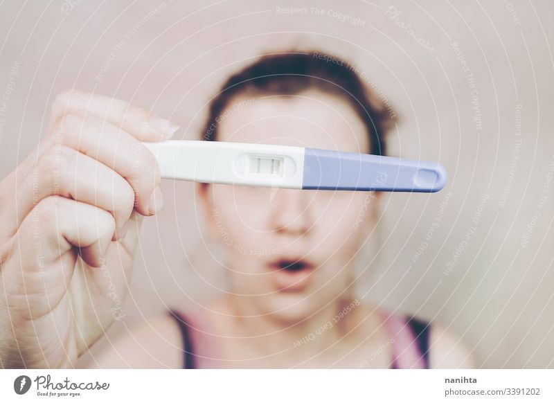 Young happy woman holding a positive pregnancy test pregnant mom mother family happiness mood emotion emotive optimism femininity feminine pink growth life