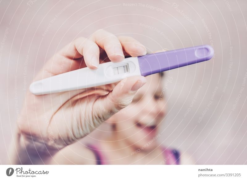 Young happy woman holding a positive pregnancy test pregnant mom mother family happiness mood emotion emotive optimism femininity feminine pink growth life