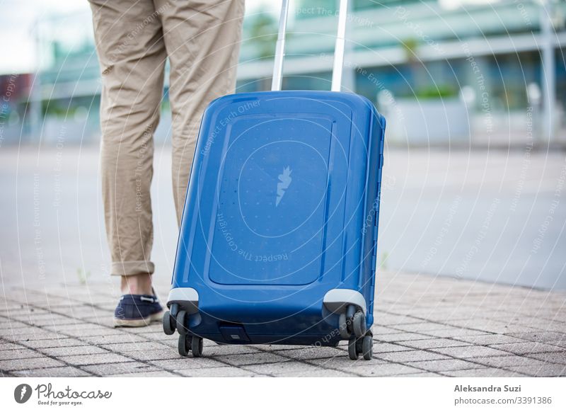 Stylish man walking to airport with blue suitcase. Businessman traveling. arrival bag baggage building business businessman carry casual city clothing confident