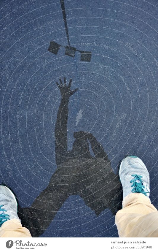 man silhouette reflected on the puddle, water reflection person human ground land shadow rain rainy day outdoors legs sneakers arm street lamp gesture concept