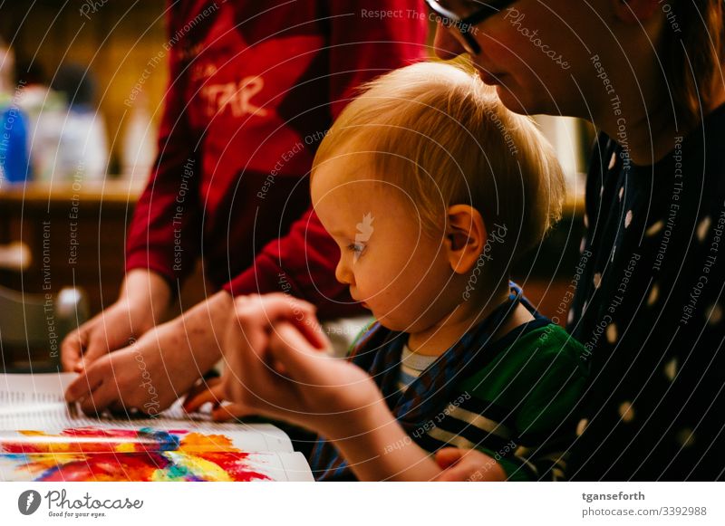 little boy reads a magazine with mother and sister Toddler Study Child Colour photo Parenting Infancy Shallow depth of field Interior shot Human being