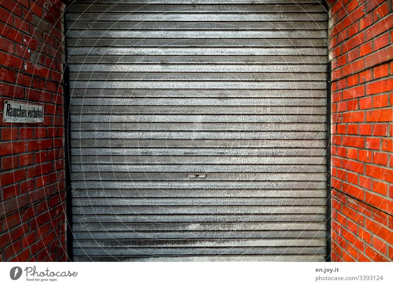 Garage door framed by a brick wall with a prohibition sign Smoking prohibited Warehouse Part of a building Industry Factory Goal Highway ramp (entrance)