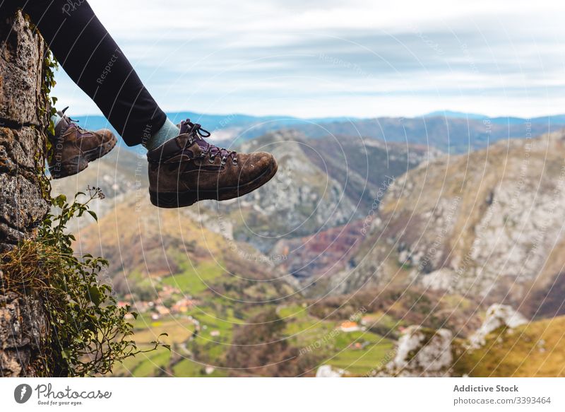 Traveler legs enjoying landscape while sitting on edge of rock against misty highland traveler cliff mountain trekking viewpoint freedom height adventure relax