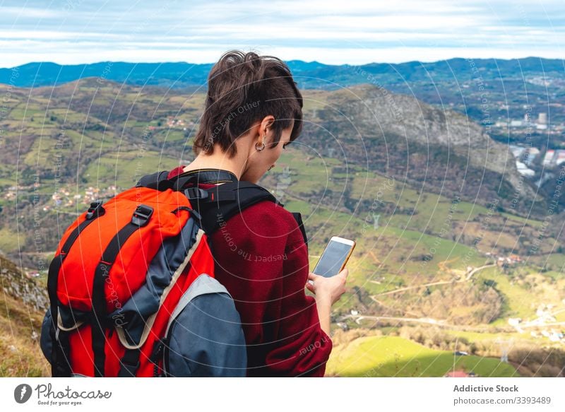 tourist with backpack and smartphone hiking on hill road under cloudy sky in Spain woman hike trekking tourism adventure footpath travel pathway scenic quiet