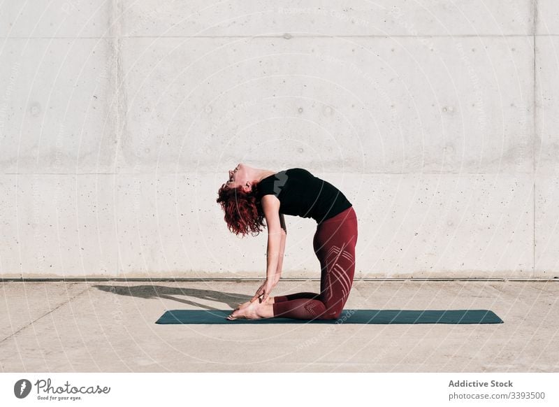 Woman doing yoga in camel pose on street woman stretch practice asana training exercise flexible athlete calm gymnastic concrete urban wellness female wellbeing