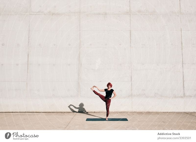 Woman doing extended hand to big toe yoga pose on street woman stretch practice asana training exercise flexible athlete calm gymnastic concrete urban wellness