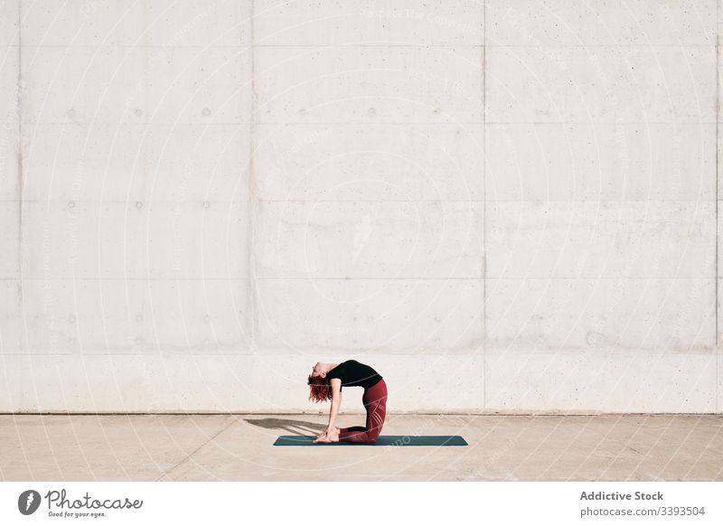 Woman doing yoga in camel pose on street woman stretch practice asana training exercise flexible athlete calm gymnastic concrete urban wellness female wellbeing