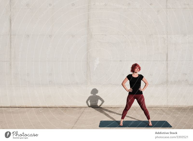 Woman athlete resting standing on yoga mat after training woman street pensive think fit tranquil female confident thoughtful trendy sportswear concrete city