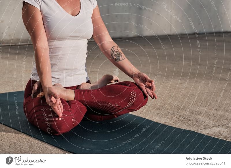 Anonymous woman meditating in lotus pose on street meditate yoga tranquil practice gyan mudra flexible idyllic gymnastic athlete padmasana barefoot concrete