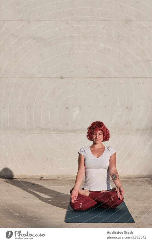 Woman with eyes closed meditating in lotus pose on street during sunset woman meditate yoga tranquil practice gyan mudra flexible idyllic gymnastic athlete