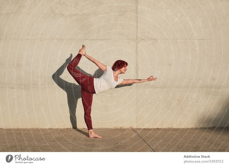 Woman doing yoga in lord of the dance pose on street woman stretch practice asana training exercise flexible athlete calm gymnastic concrete urban wellness