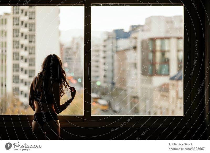 Unrecognizable young woman in lingerie at window sensual dream cityscape seductive sensitive slim touch hair female feminine tender temptation passion natural