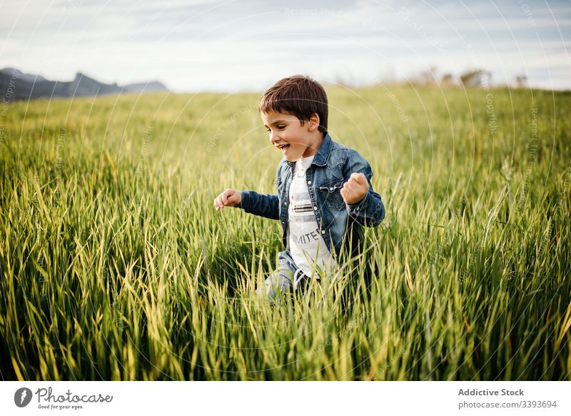 Happy boy enjoying green field in countryside run grass fun happy playful tall rural freedom cloudy walk kid child nature male childhood pleasure peaceful