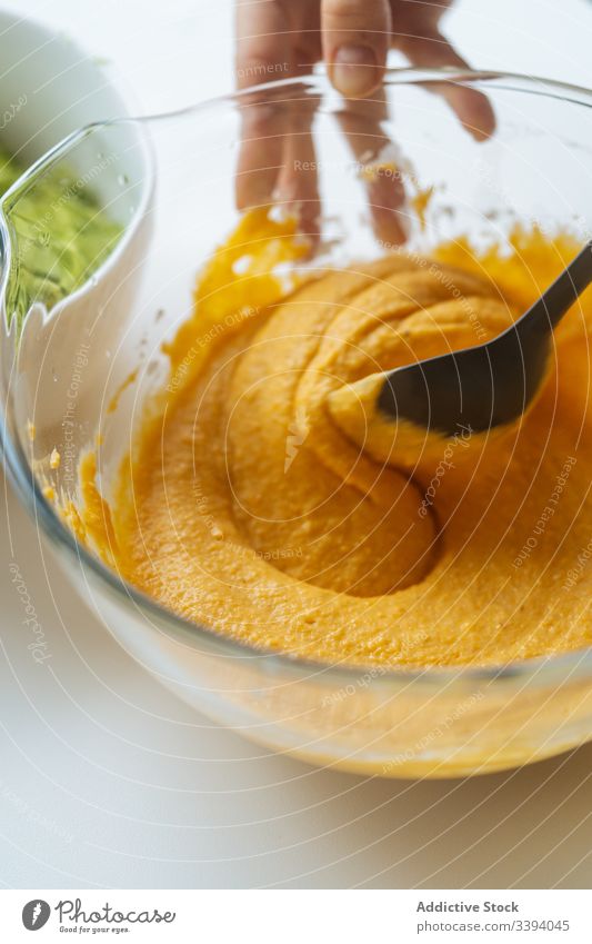 Woman stirring vegetable puree in bowl at table cook mixture orange glass cuisine healthy kitchen food vegan lunch homemade dinner cream ingredient vegetarian