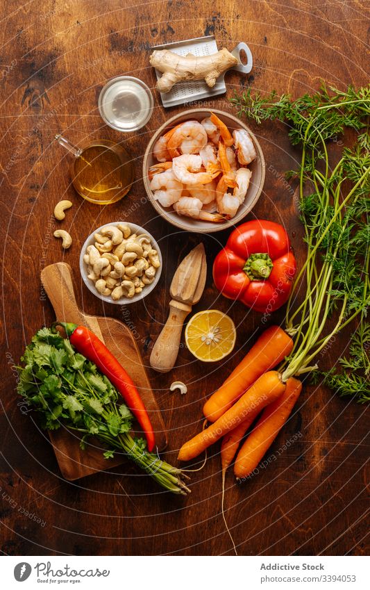 Fresh ingredients for shrimp dish cook kitchen vegetable juicer food preparation home meal tool ginger water oil cashew nut carrot pepper lemon herb parsley