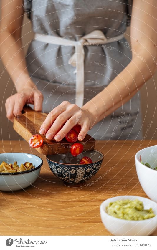 Crop woman spilling tomatoes into bowl cook salad cherry tomato add vegan healthy kitchen dish food preparation home meal ingredient culinary cuisine organic