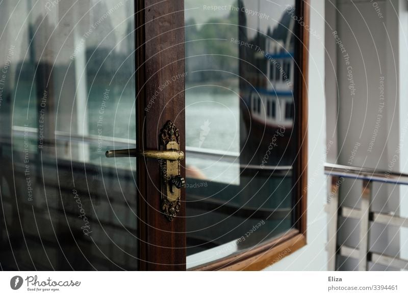 Detail of a golden door handle on a glass door in front of a window with wooden frame on a ship Gold Wood wooden frames reflection Glass boat Door lock Railing