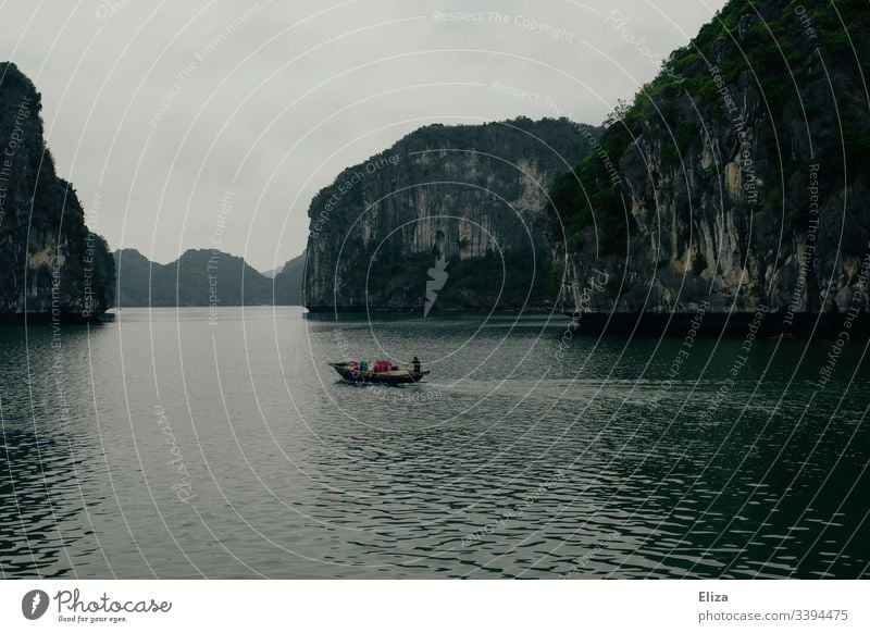 A fishing boat on the sea in Halong Bay in Vietnam; beautiful landscape with limestone rocks rising out of the sea in foggy weather Halong bay Ocean