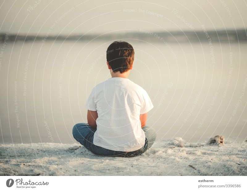 Back view of a Pensive child sitting on the beach childhood nostalgic thoughtful Thought loneliness lonely expression freedom innocence portrait serious dream