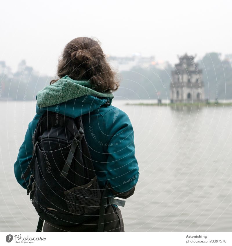 Young woman looks out over Lake Hoan Kiem in Hanoi, Vietnam Hoan Kiem Lake Woman teen Hair Back Rear view Jacket Hooded (clothing) Human being