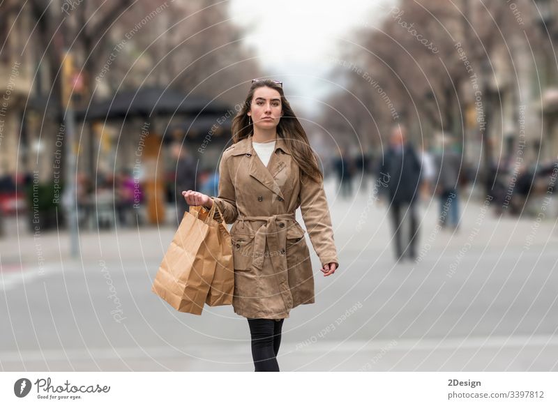 Young woman walking in the street holding shopping handbag teenage mixed race barcelona beautiful fall asian europa happy shopper fashion spain city downtown