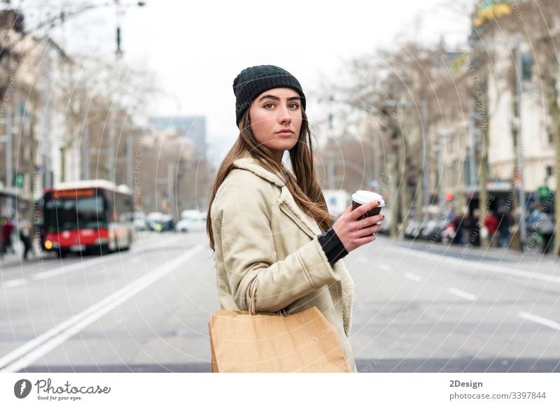 Portrait of young european woman walking in a city street, with takeaway coffee in hands modern town alone beautiful cup attractive urban downtown girl stroll