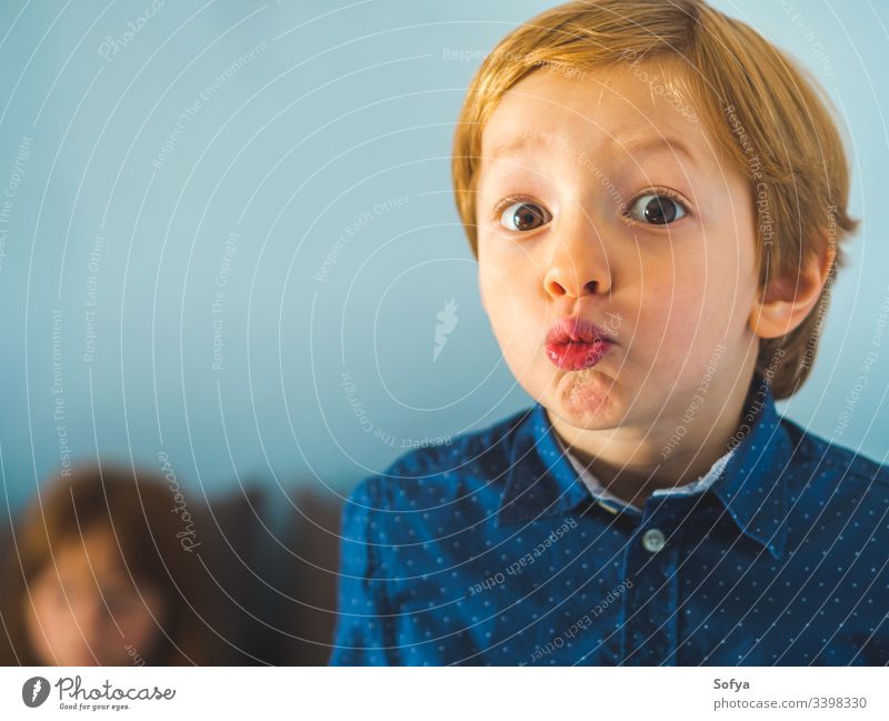 Little blonde boy making funny expression. Closeup portrait child little kid face caucasian shirt blue fashion eyes look vivid lively person skin surprise