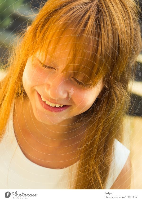 Closeup of cute smiling redhead girl with closed eyes in white dress in summer. little child smile portrait happy fringe fashion floral party flower wedding kid