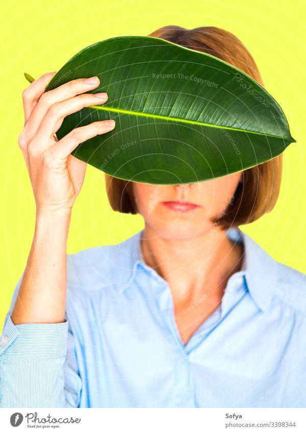 Young woman portrait on yellow with rubber fig leaf beauty beautiful unique environment concept hand selfconfident shirt girl white background soft face