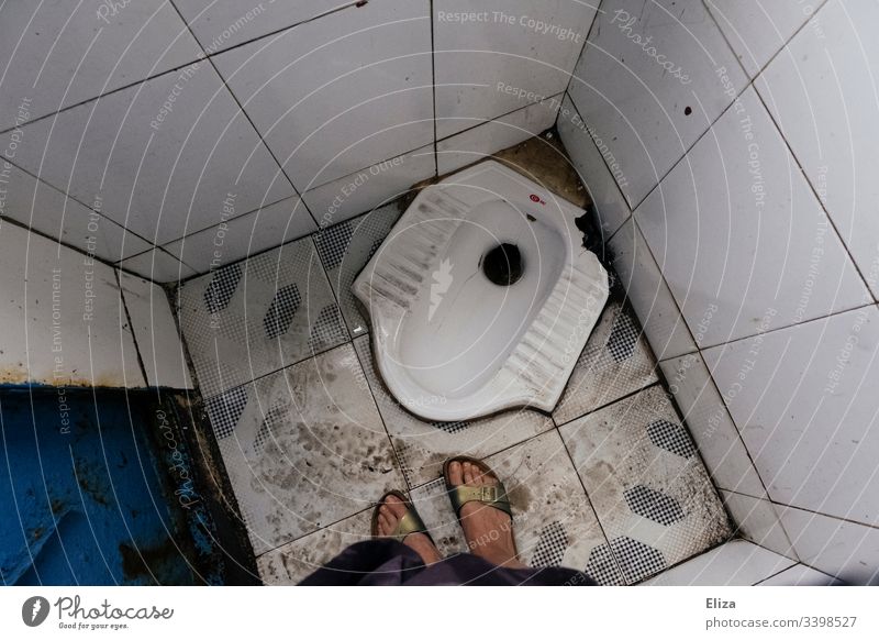 A bird's-eye view of a dirty squatting toilet with female feet on it in Southeast Asia Toilet Crouch unaccustomed john Woman disgusting travel South East Asia