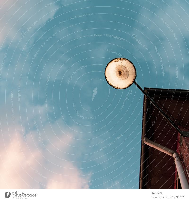 View of a street lamp on the house wall from below against a cloudy sky Minimalistic Lamp Street lighting Lantern Flag flag Blue sky Blue background Summer