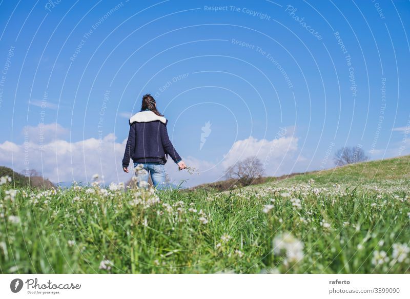 Rear view of a brunette Hispanic woman in casual clothes walking on the field Field Flower Green Back Freedom Spring 1 Woman Nature on one's own Summer